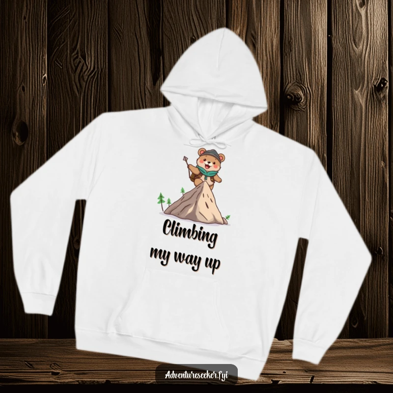 Funny hoodie showcasing a cute bear adventurer character happily scaling a small mountain, radiating warmth and a playful, adventurous spirit.