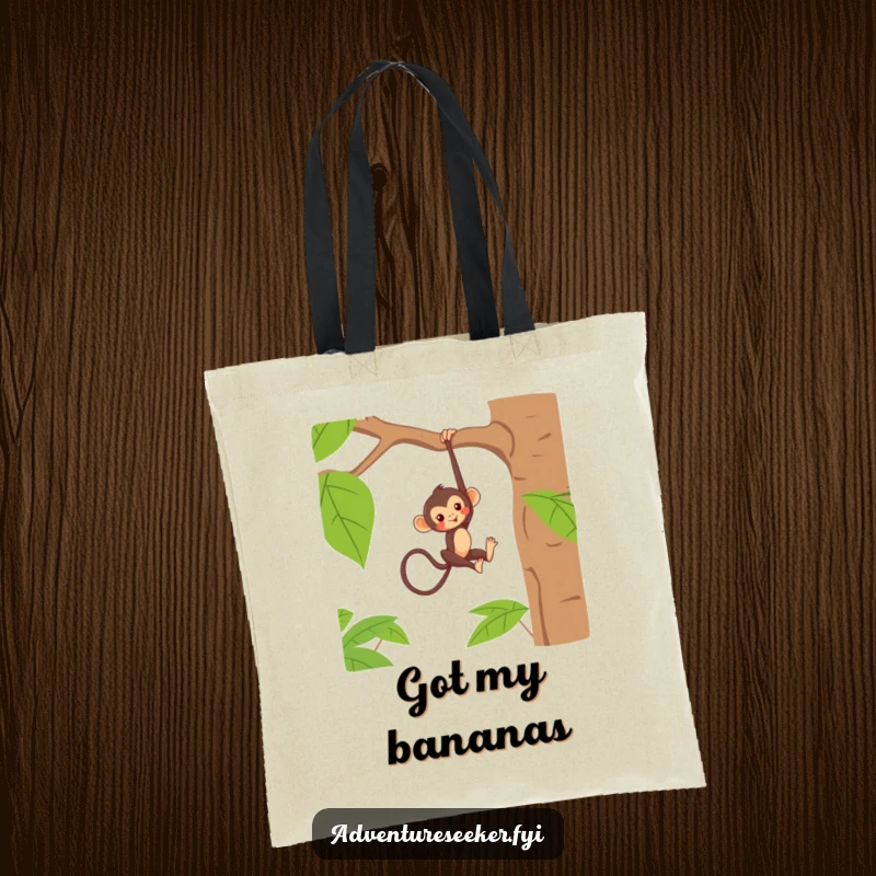 Funny tote bag with a mischievous monkey character hanging playfully from a jungle tree branch, showcasing a fun design.